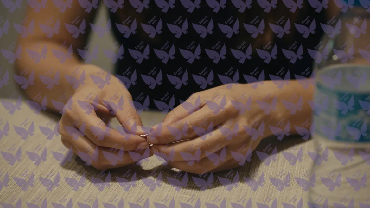 Руки держат серебряную серьгу и бутылку воды, фон полностью размыт.